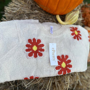 Relaxed fit boucle fabric floral knit cropped sweater is adorned w/ red and yellow flowers. Crew neck & long sleeves.