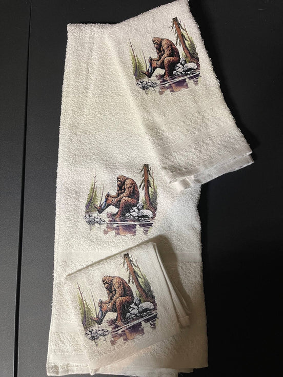 Bathing Bigfoot 3-piece towel set by Squatchin’ Country featuring plush towels with Bigfoot and forest-themed designs