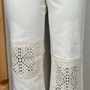 Judy Blue ecru jeans with crocheted patches featuring intricate stitching and textured fabric details.