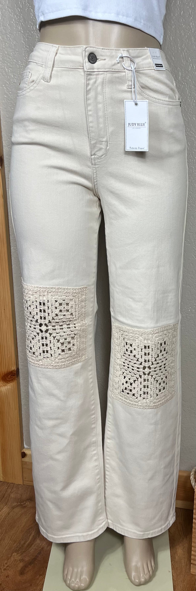 Judy Blue ecru jeans with crocheted patches featuring intricate stitching and textured fabric details.