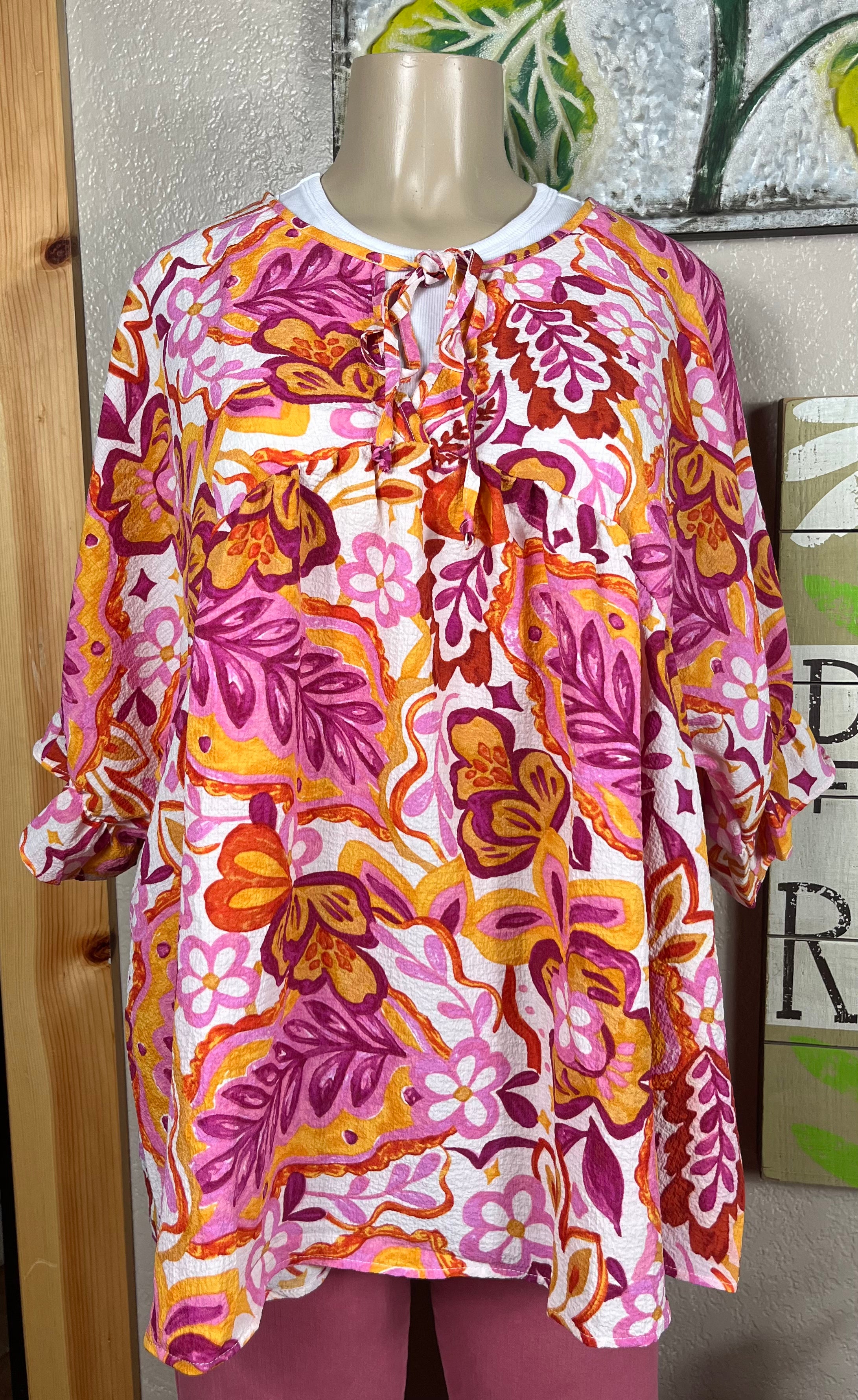 ADORA LA peasant floral top with billowy sleeves and a v-neck, featuring colorful floral patterns and lightweight fabric.