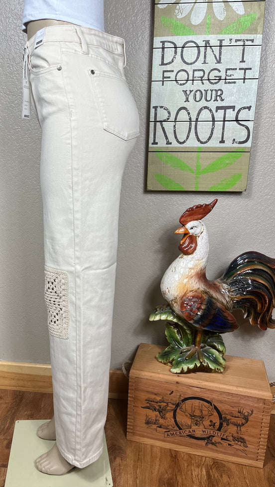 Judy Blue ecru jeans with crocheted patches, showcasing detailed beige and white crochet designs on denim fabric.