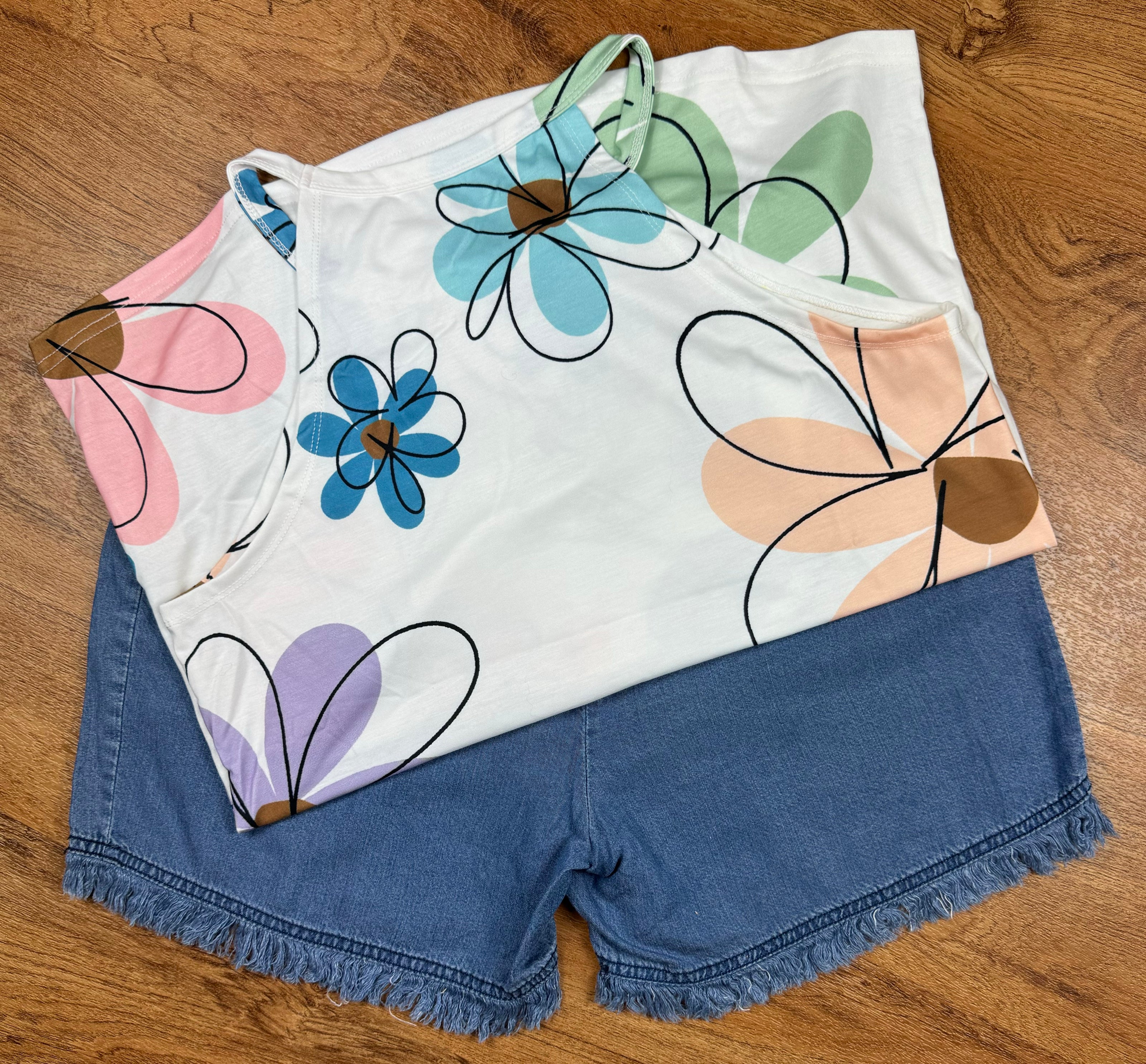 Aapparella sleeveless tank top with large floral print, vibrant colors, and a relaxed fit, perfect for casual summer wear.