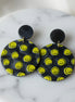 Avenue Zoe Happy Face Dangles earrings with cheerful face design and gold-tone hooks, hanging against a neutral background.