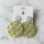 Avenue Zoe Happy Face Dangles earrings featuring cheerful smiling face charms on gold-tone hooks.