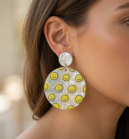 Avenue Zoe Happy Face Dangles earrings with cheerful face design and gold-tone hooks on a white background