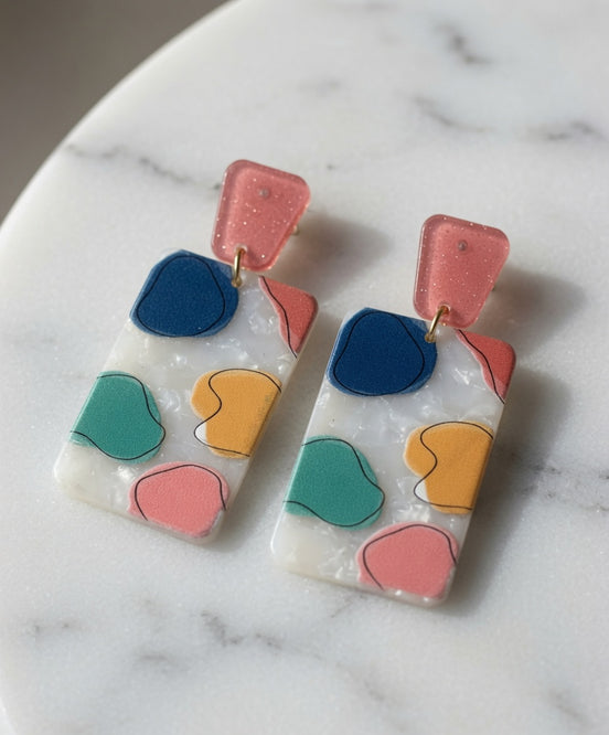 Avenue Zoe rectangular abstract dangle earrings with geometric design and mixed metal finishes hanging on display