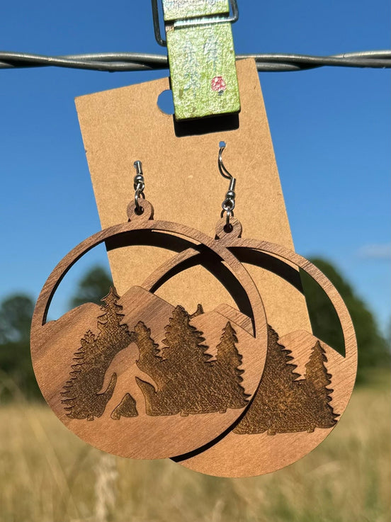 Wooden Bigfoot earrings by Krafty Supply featuring carved Sasquatch designs on natural wood dangle earrings.