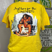 Squatchin’ Country Bigfoot roasting marshmallows graphic T-shirt featuring a Bigfoot figure with marshmallows over a campfire.