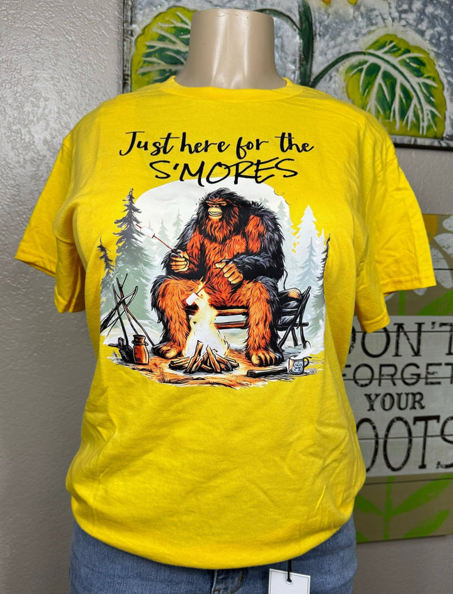 Squatchin’ Country Bigfoot roasting marshmallows graphic T-shirt featuring a Bigfoot figure with marshmallows over a campfire.