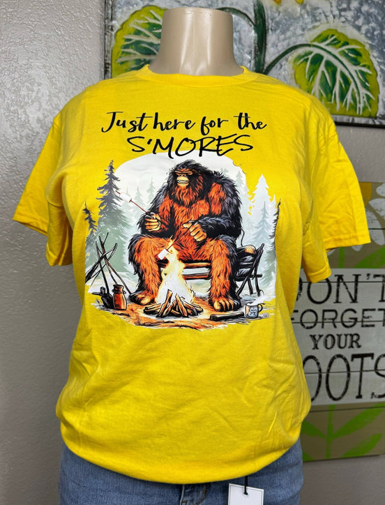 Squatchin’ Country Bigfoot roasting marshmallows graphic T-shirt featuring a Bigfoot figure with marshmallows over a campfire.