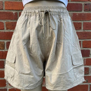 Khaki wide leg cargo shorts by ADORA LA, showing relaxed fit and multiple side pockets on lightweight fabric.