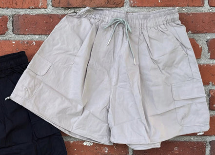 Khaki wide leg cargo shorts from ADORA LA displayed on a model, featuring multiple pockets and a relaxed fit for casual wear.
