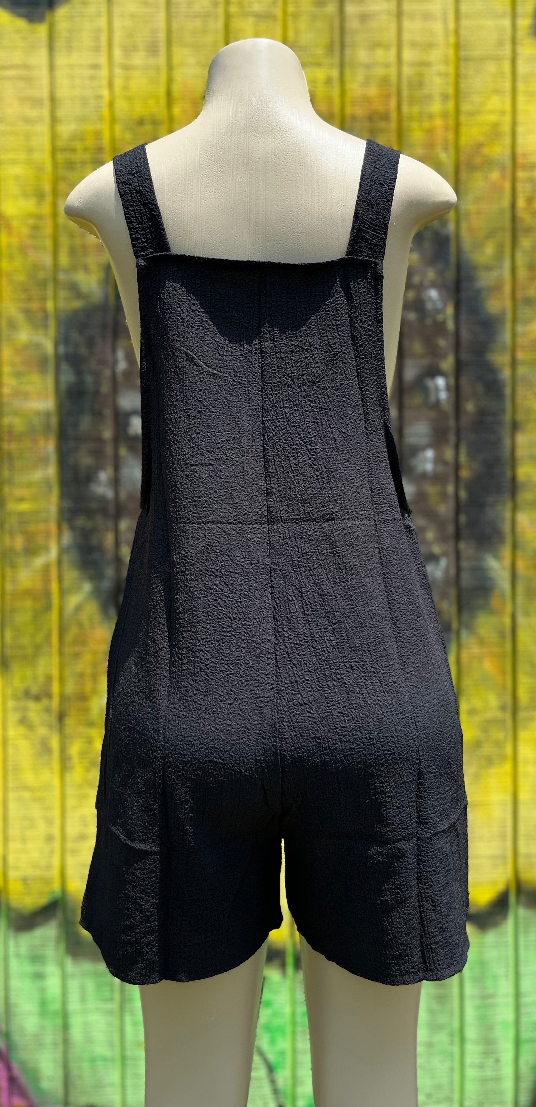Black romper by Shiying Fashion displayed on a hanger with a close-up view of the fabric and design details.