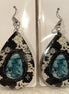 Earring Babe Boutique brand. Silver dangle, 2.5" hard material, simulated cow print with turquoise center. $7.25