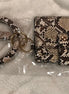 Pretty Simple brand. Snakeskin print snap wallet in beige, brown and cream. Features a tasseled key ring and gold tone rings.
