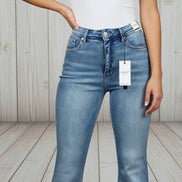 Light blue Judy Blue flare jeans with distressed details and high-waisted fit, styled with a casual top and sneakers.