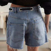 Mccolin lace-up denim shorts featuring distressed details and a high-waisted fit, showcased on a model in a casual summer setting.