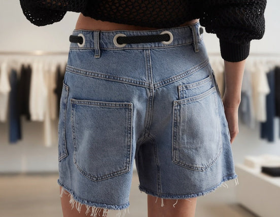 Mccolin lace-up denim shorts featuring distressed details and a high-waisted fit, showcased on a model in a casual summer setting.