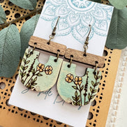 Lightweight boho maple wood earrings with hand-painted floral designs by Seasideblooms, hanging from silver hooks.