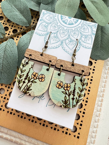 Lightweight boho maple wood earrings with hand-painted floral designs by Seasideblooms, hanging from silver hooks.