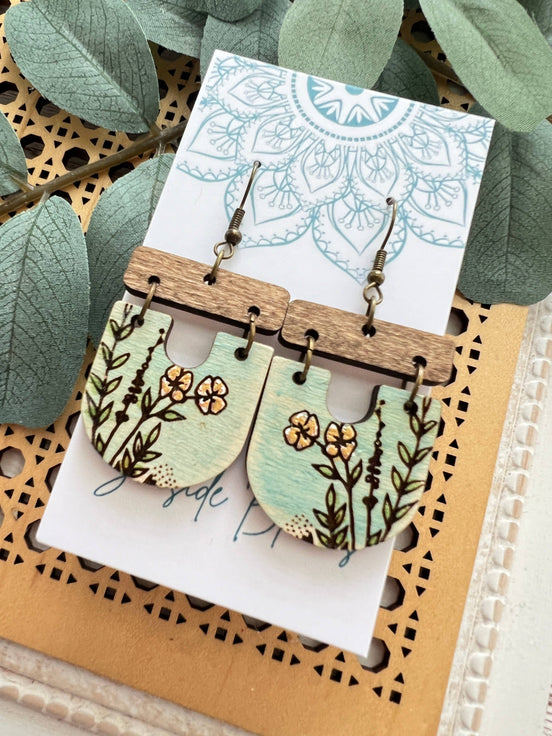 Lightweight boho maple wood earrings with hand-painted floral designs by Seasideblooms, hanging from silver hooks.