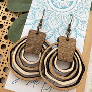 Lightweight boho wood hoops by Seasideblooms, hand-painted with colorful designs, hanging on a display.