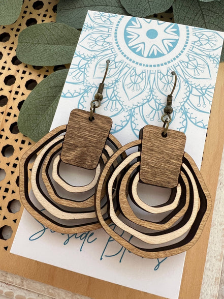 Lightweight boho wood hoops by Seasideblooms, hand-painted with colorful designs, hanging on a display.