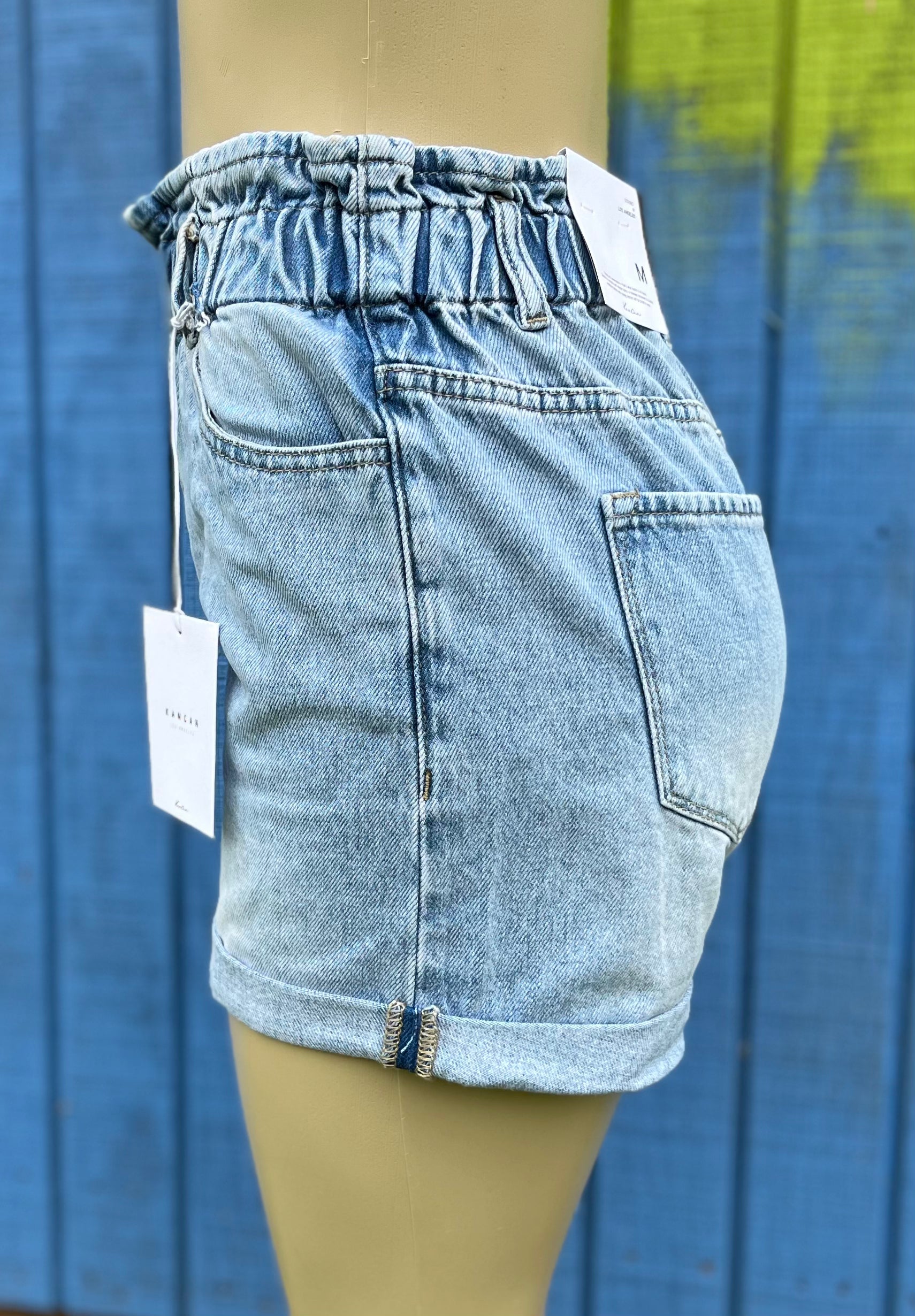 KanCan denim shorts featuring distressed details and a high-waist fit, shown on a model with casual styling.