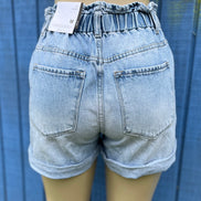 KanCan denim shorts with distressed details and frayed hem, styled on a model for a casual summer look.
