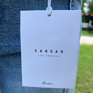 Pair of KanCan Capris with a fitted, casual style and classic denim wash, shown on a person standing outdoors.